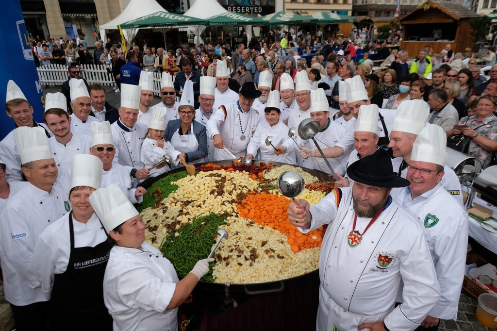Die Köche stehen auf dem Marktplatz neben einer Pfanne voll „Leipziger Allerlei“.