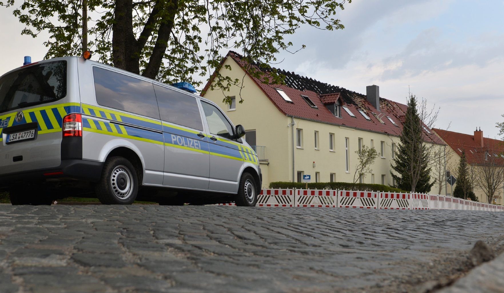 Polizei bewacht am 16.04.2015 das teilweise ausgebrannte Gebäude einer geplanten Unterkunft für Asylbewerber in Tröglitz (Sachsen-Anhalt).