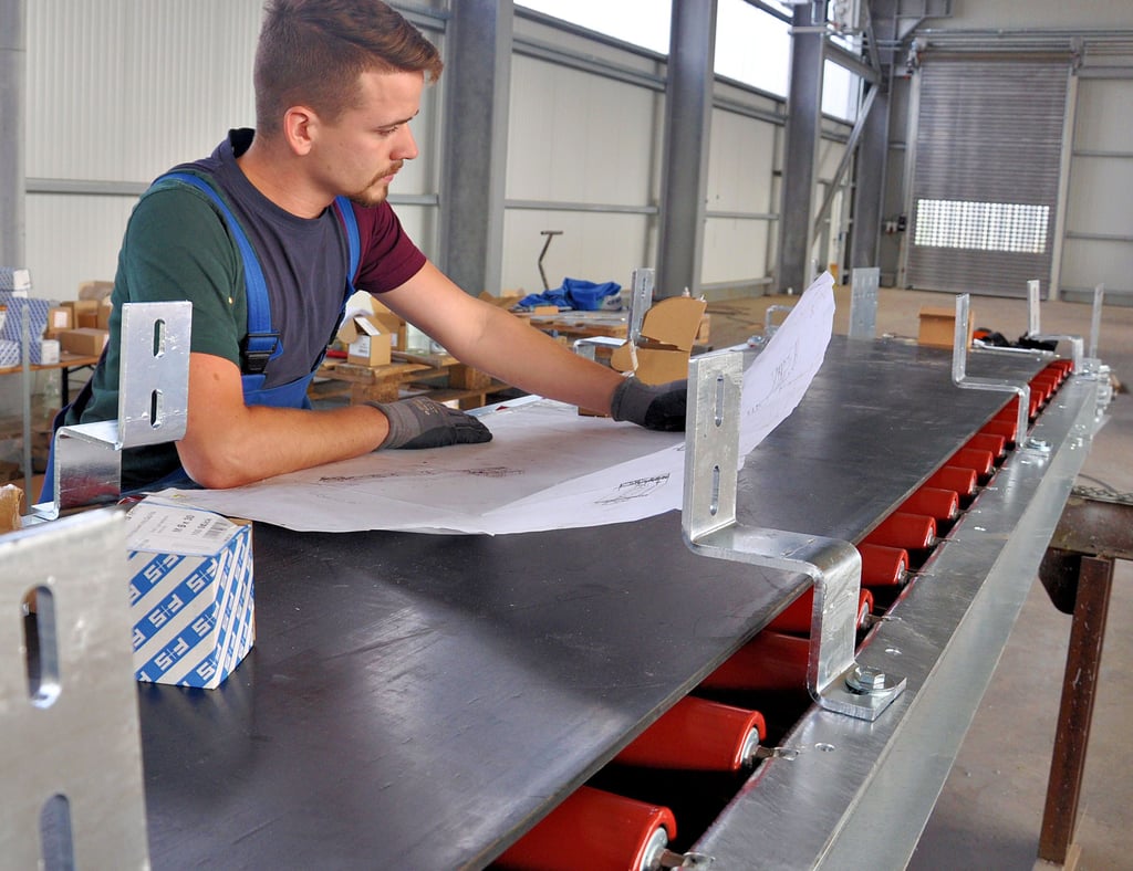 Maximilian Straube studiert Unterlagen zur Montage einer Förderanlage von ABP Maschinenbau.