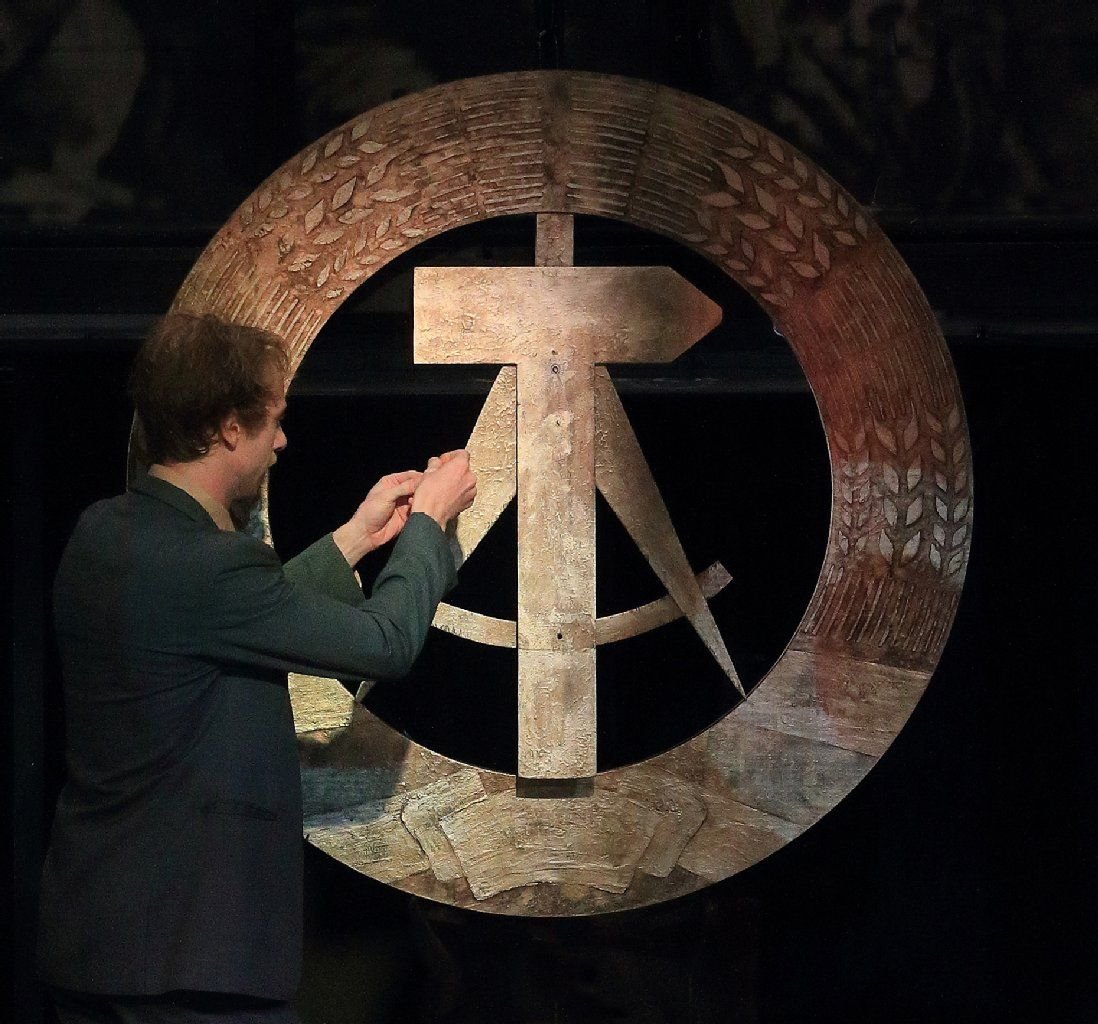 Schauspieler Raimund Widra in der Rolle des Parteisekretärs Horrath steht während der Generalprobe zum Stück "Spur der Steine" im Schauspielhaus in Magdeburg vor dem Emblem der Deutschen Demokratischen Republik.