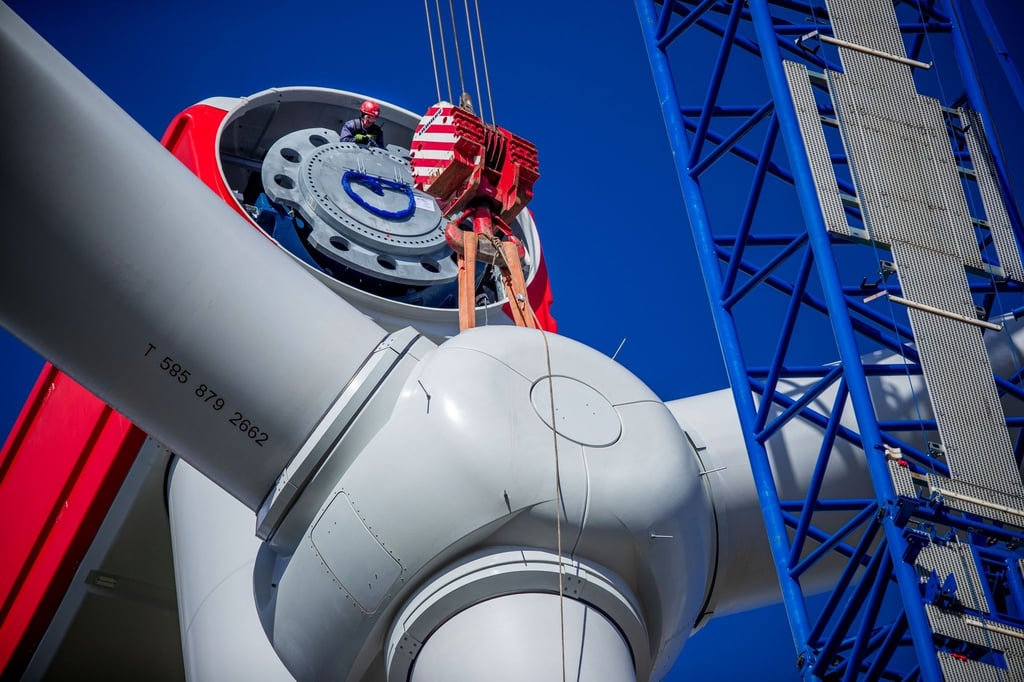 Mit einem Spezialkran wird der vormontierte Propeller an das Maschinenhaus einer Windkraftanlage gehoben.