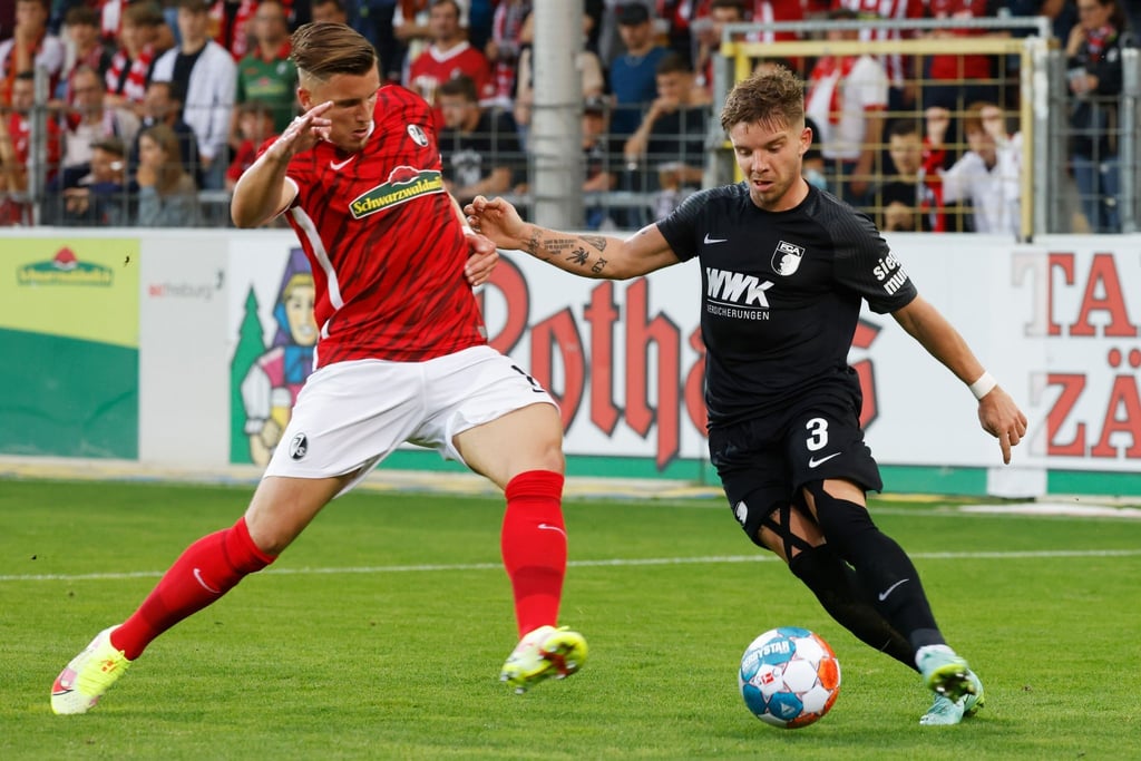 Freiburgs Ermedin Demirović (l) im Duell mit Augsburgs Mads Pedersen.