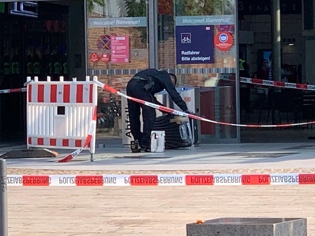 Der leere Koffer am Eingang des Hauptbahnhofs in Halle wird von einem Beamten abtransportiert.