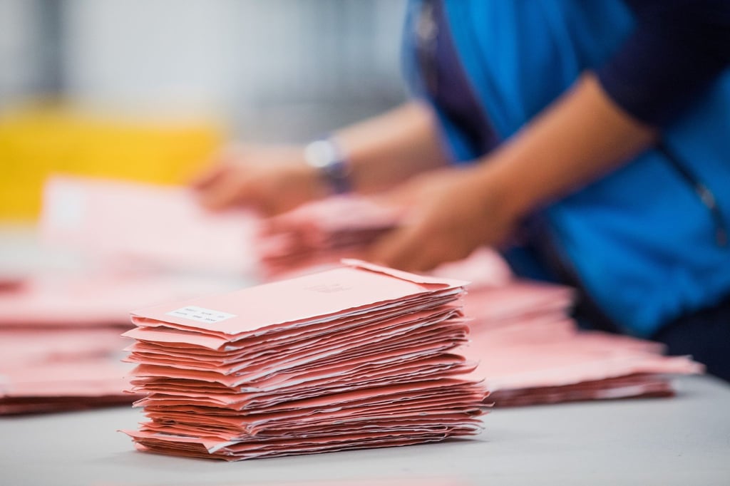 Eine Wahlhelferin sortiert Wahlbriefe.