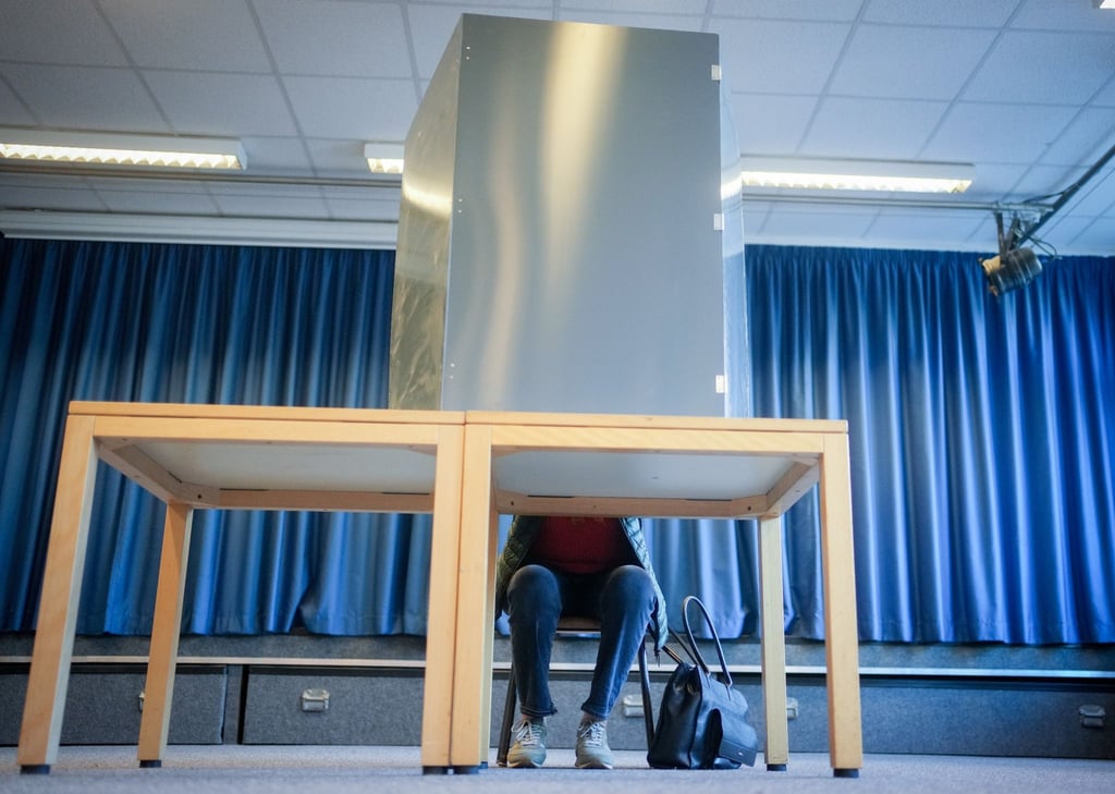 Eine Wählerin sitzt in der Wahlkabine für die Bundestagswahl.