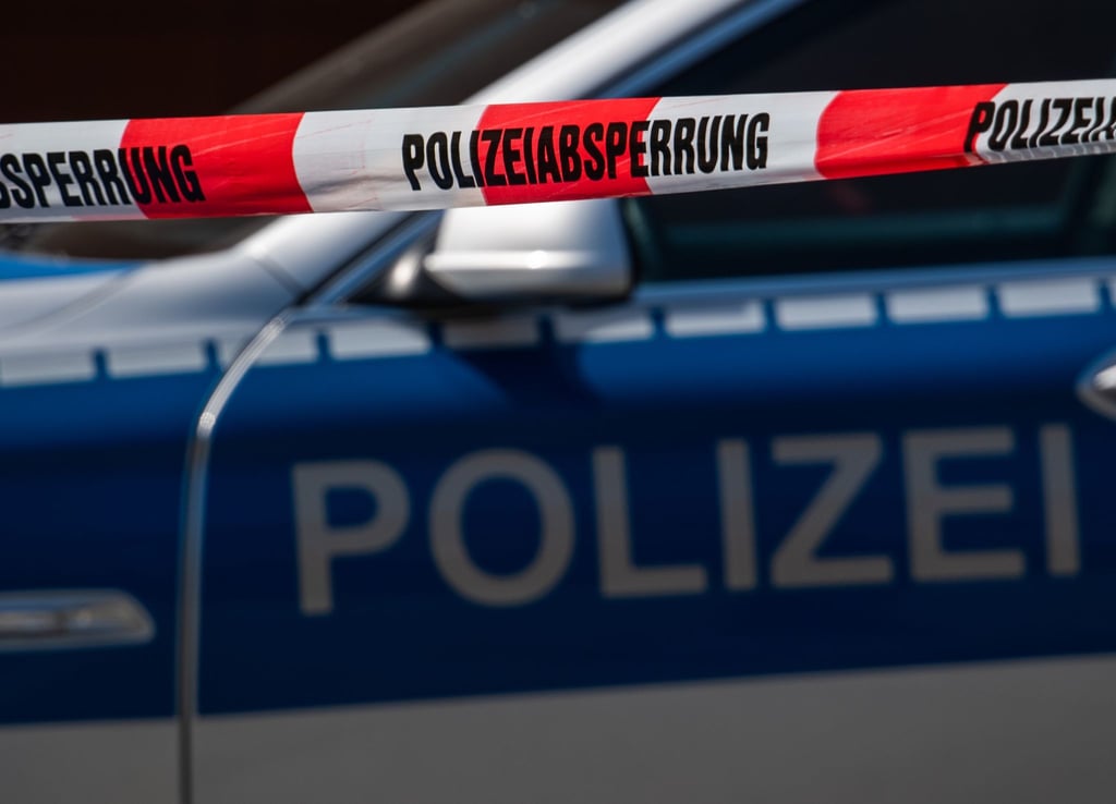 Ein Polizeiauto steht hinter Absperrband mit der Aufschrift Polizeiabsperrung.