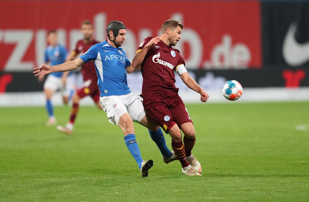 Damian Roßbach (l) von Hansa Rostock und Simon Terodde vom FC Schalke 04 kämpfen um den Ball.