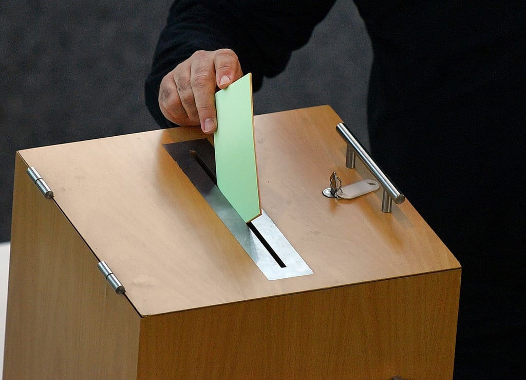 Ein Stimmzettel wird in die Wahlurne geworfen.