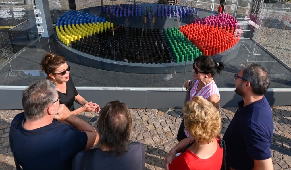 Interessierte Bürger stehen vor einem Pavillon auf der Einheitsexpo 2021 in Halle (Saale) und betrachten die Präsentation des Bundestages. Die Stadt in Sachsen-Anhalt richtet in diesem Jahr die zentrale Feier zum Tag der Deutschen Einheit aus.