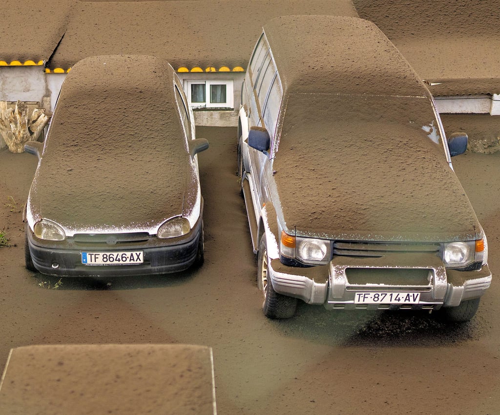 Eine Ascheschicht bedeckt Straßen, Autos und Häuser.