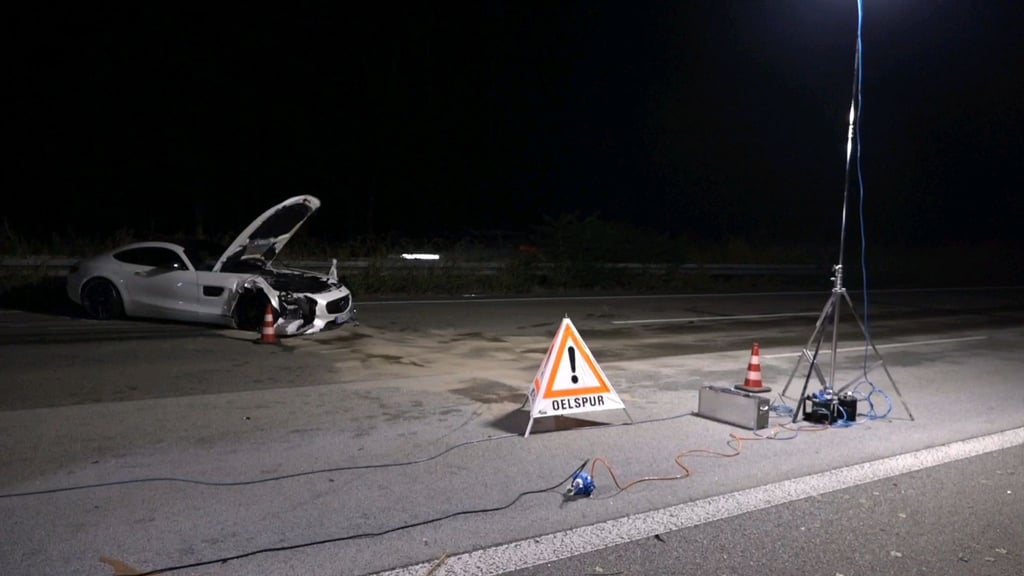 Ein Warndreieck steht nach einem schweren Unfall auf der A67 vor einem zerstörten Auto auf der Straße.