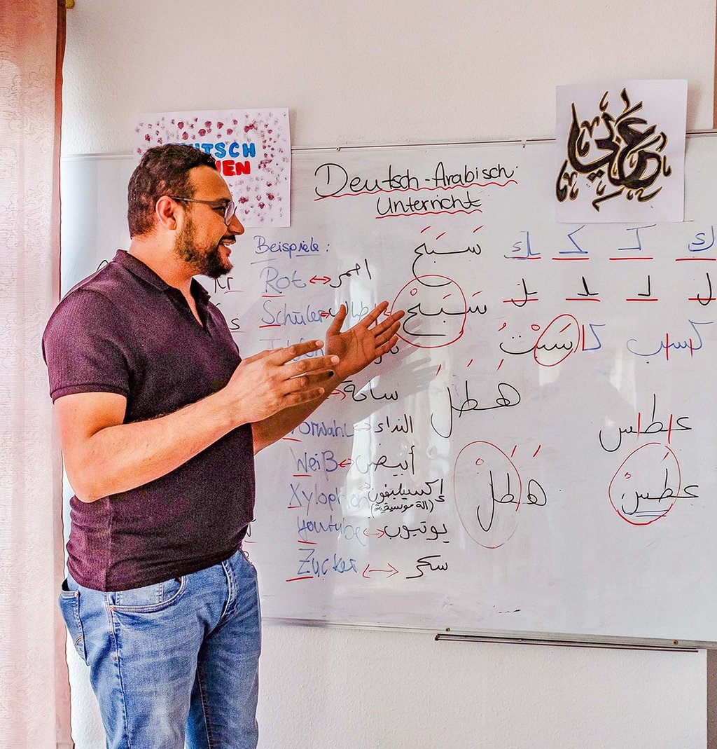 Mohanad Aljassem Alabo, der Vorsitzende von Salam, an einer Tafel mit arabischer Schrift. Hier kann man die Sprache lernen.