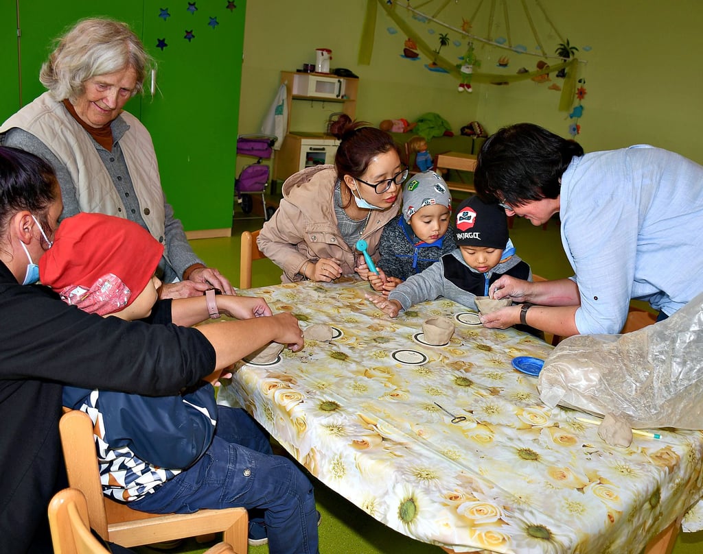 Töpfern in der Kita Fleetmark: Künstlerin Helga Geissler (zweite von links) und Andrea Schulz-Strömer (rechts), Leiterin der Einrichtung, unterstützen Kinder sowie Erwachsene.