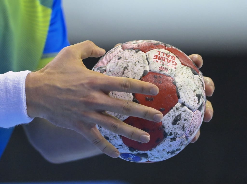 Ein Handballspieler hält den Spielball in den Händen.