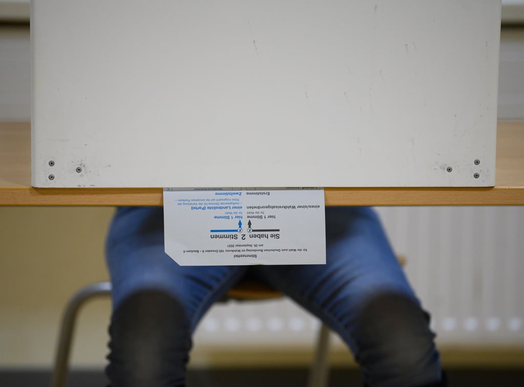 Ein Wählerin sitzt im Wahllokal mit ihrem Stimmzettel in der Wahlkabine.