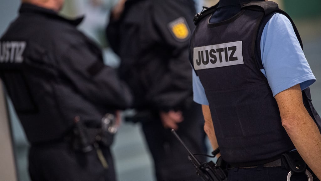 Polizisten tragen Westen mit der Aufschrift "Justiz".