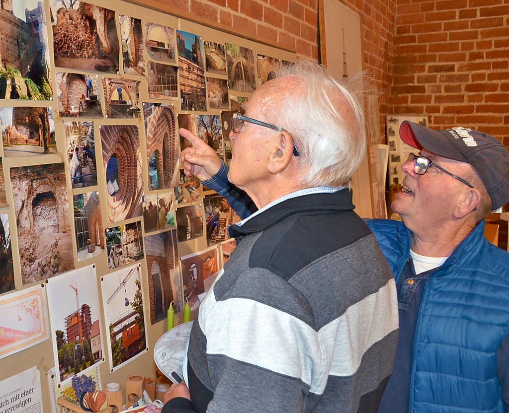 Kirchenführer Wolfgang Hellwig zeigt Werner Leuchtenberg, wie der zerschossene Kirchturm vor dem Wiederaufbau aussah.