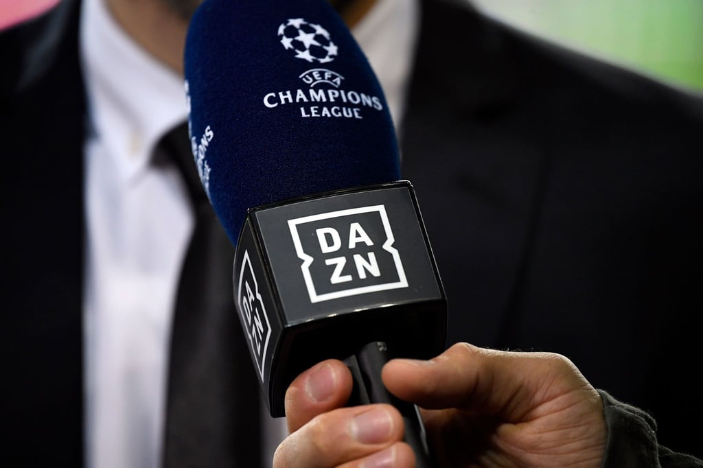 Ein Reporter hält ein Mikrofon des Streamingdienstes DAZN während eines Interviews fest.