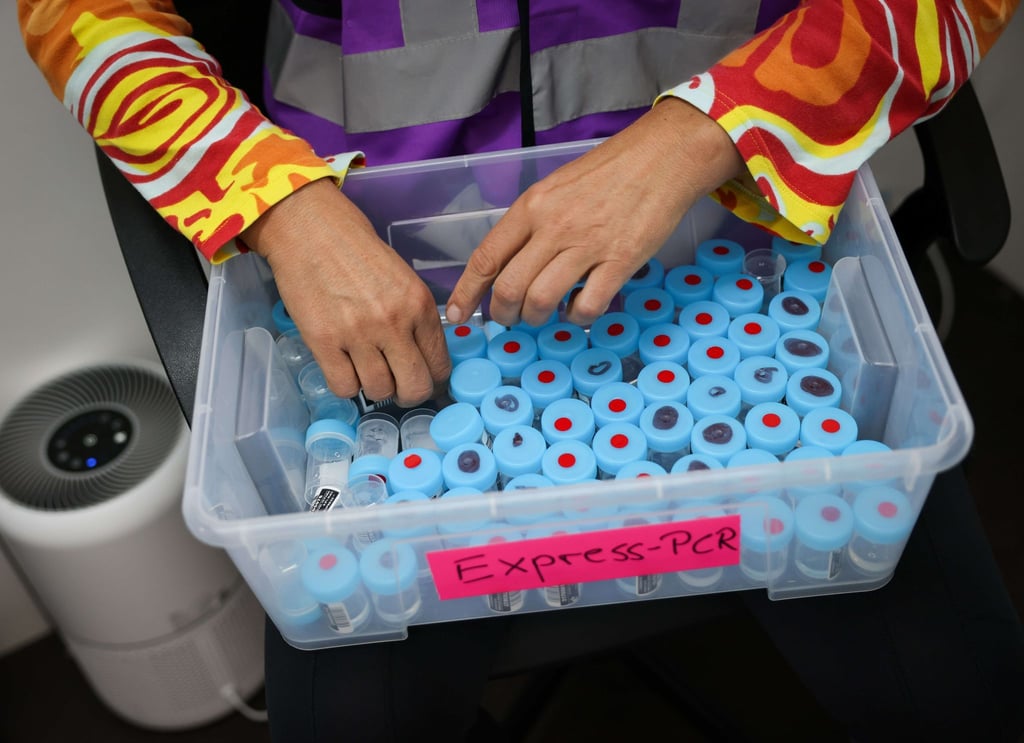 Eine Mitarbeiterin sortiert noch unbenutzte Behälter für einen PCR-Gurgeltest in einem Testcenter für Corona-Schnelltests (Antigentest) und Corona-PCR-Tests.