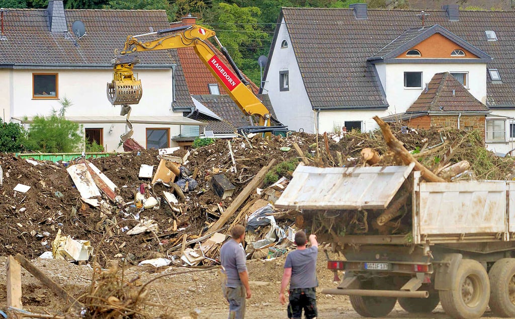 Bagger laden Bauschutt und Treibgut auf LKW in dem von der Hochwasser-Katastrophe zerstörten Dorf Kreuzberg an der Ahr.
