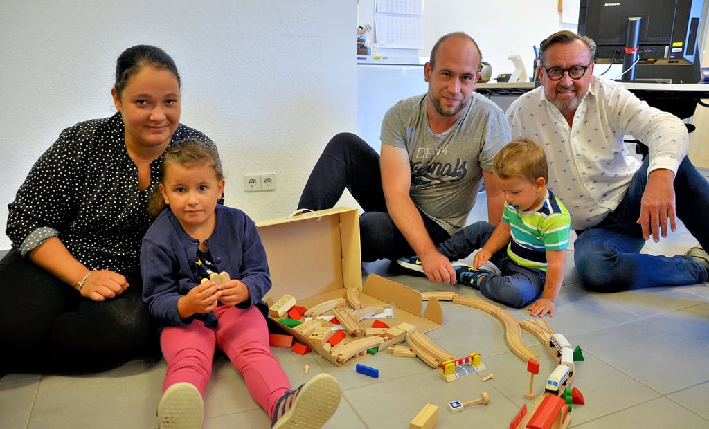Nach dem Brand des Wohnhauses in der Salzer Straße ist auch die Wohnung von Mama Liz Lorente fon Seca (von links), Töchterchen Leony Melina (5), Papa Tim Eichstädt und Sohnemann Elias Tim (3) nicht mehr bewohnbar. Tim Eichstädts Chef Peter Liensdorf (rechts) hat deshalb eine Spendenaktion ins Leben gerufen, um der Familie zu helfen. Die Holzeisenbahn im Bild ist eine der Spenden, die die Familie schon erreicht hat. Ein ehemaliger Mitarbeiter hatte sie vorbeigebracht ? und auch ein bisschen Geld dagelassen.