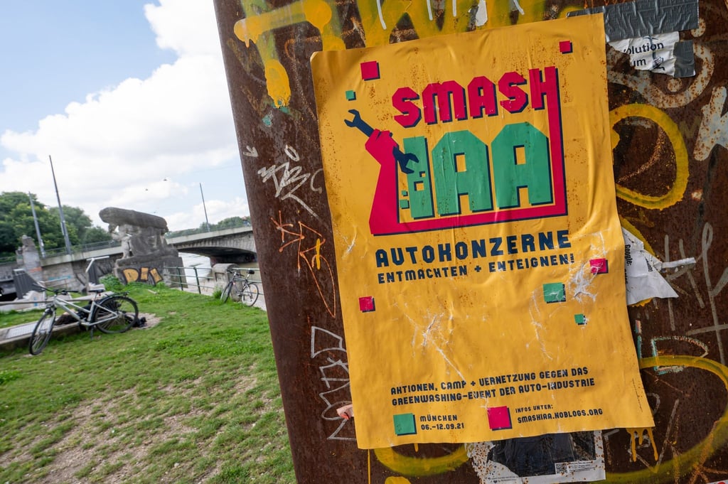 Ein gelbes Plakat mit der Aufschrift „Smash IAA Autokonzerne entmachten und enteignen!“ klebt an einer Wand in der Stadt.