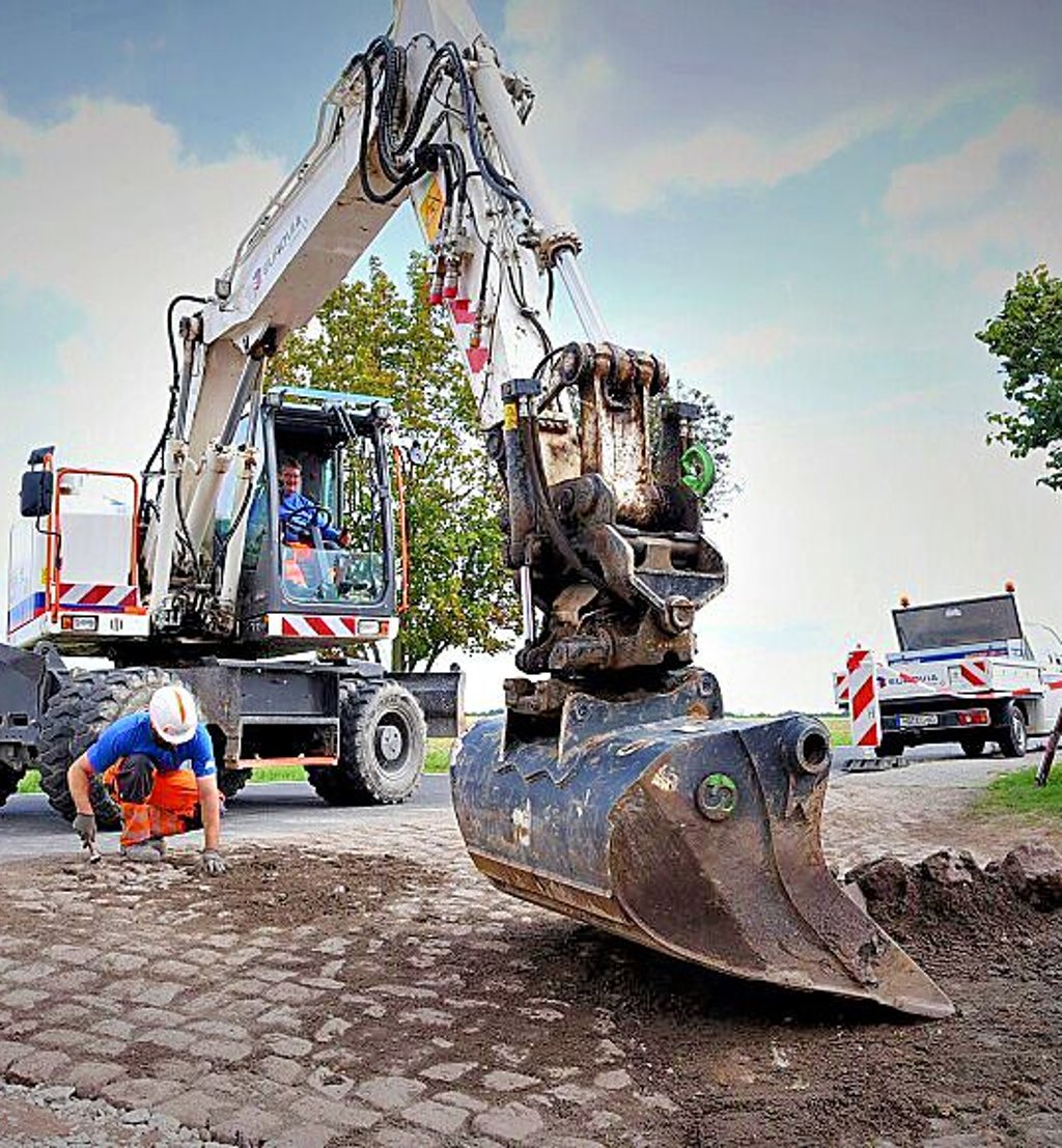 Arbeiter pflastern Randbereiche an der Straße.