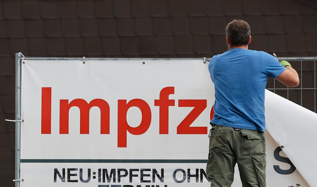 Ein Arbeiter entfernt die Plane an der Einfahrt zum Impfzentrum.