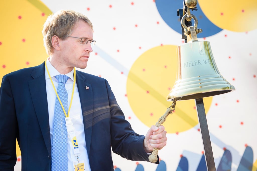 Daniel Günther (CDU) läutet („Glasen“) zur offiziellen Eröffnung der Kieler Woche auf einer Bühne im Olympiastützpunkt Schilksee eine Schiffsglocke.