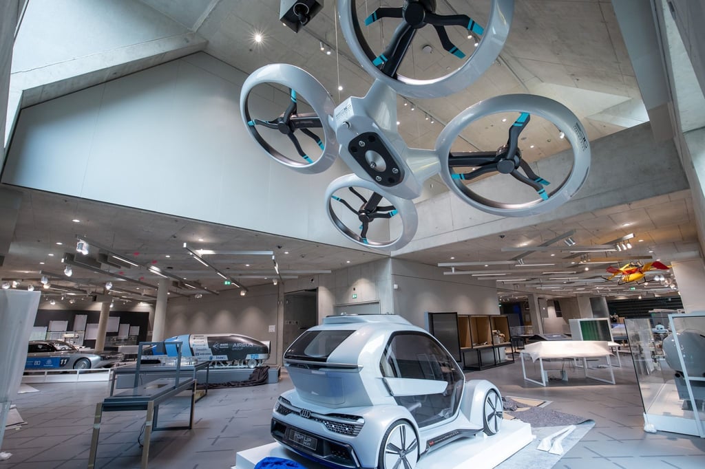 Die Passagierdrohne "Pop.Up Next" (v) steht in den Ausstellungsräumen vom Zukunftsmuseum, der Zweigstelle des Deutschen Museums München, neben dem Prototyp für das Hyperloop-Projekt (M) und das Solarauto blue.cruiser (l).