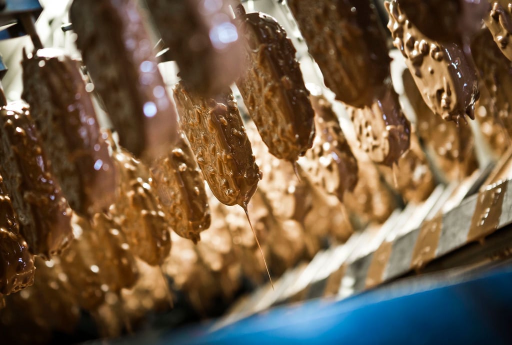 Schokolade tropft bei der Produktion von Speiseeis vom Schokomantel.