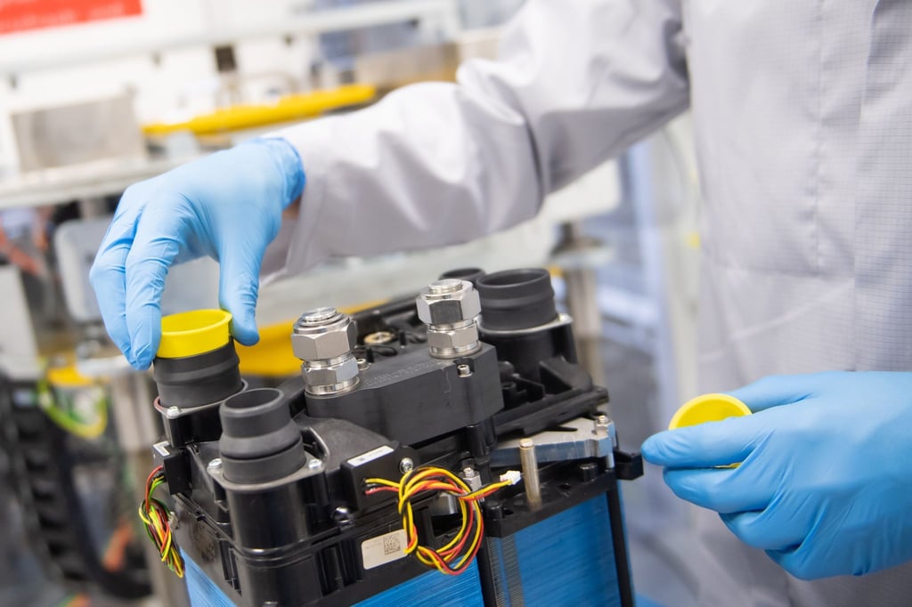 Ein Mitarbeiter eines Autozulieferers arbeitet an der Montage eines Medienmoduls auf einem Brennstoffzellenstack.