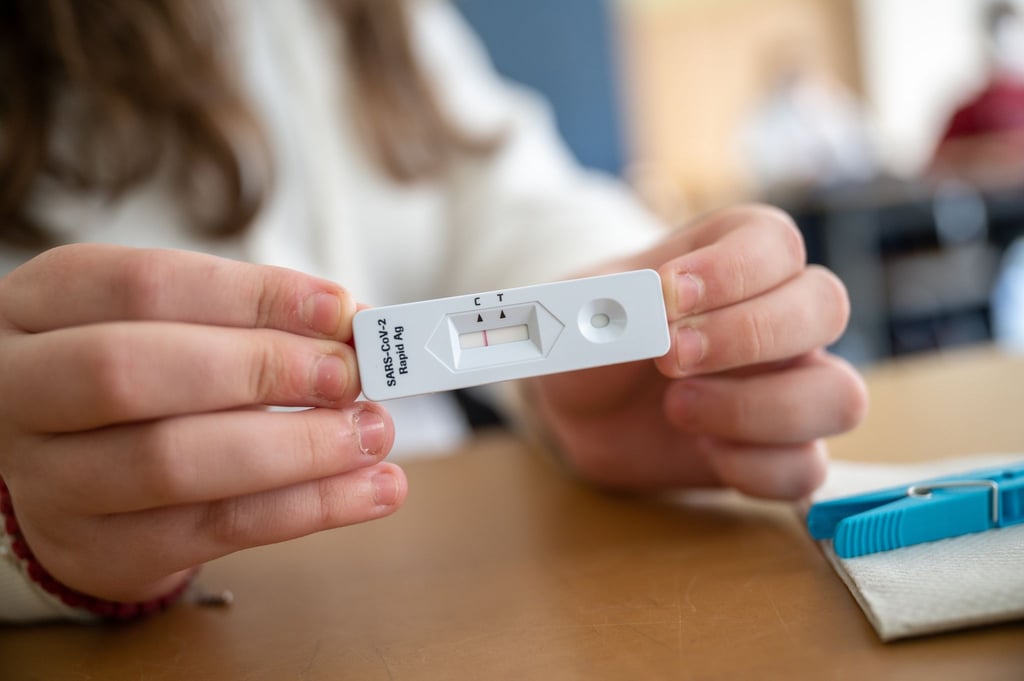 Ein Schülerin zeigt in einer Klasse ihren negativen Corona-Schnelltest.