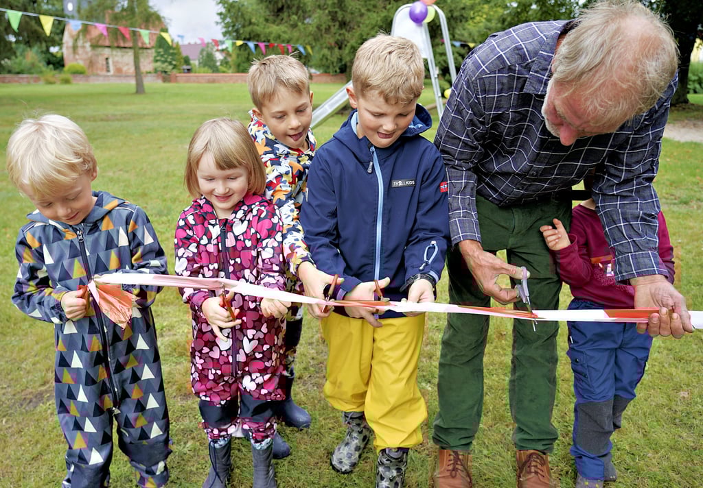 Schnipp, schnapp ? und jetzt ist der Spielplatz für die Kinder da. Ortsbürgermeister Gerd Bunjes schneidet in vereinter Anstrengung mit den Jüngsten des Ortes das Absperrband durch.