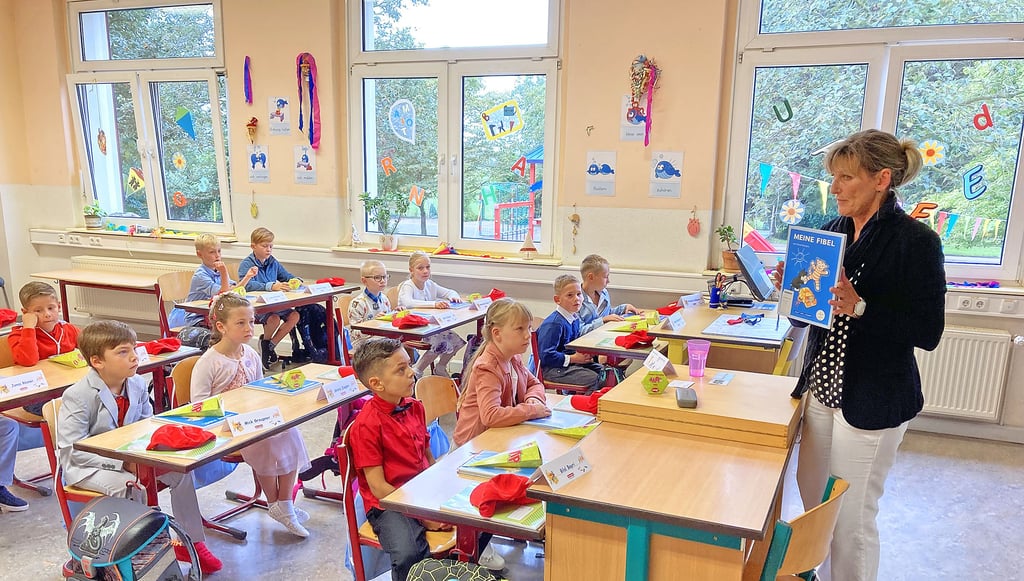 Zum ersten Mal im Klassenraum: Lehrerin Angela Kühling zeigt ihrer neuen ersten Klasse die Fibel, mit der sie ab diesem Montag lernen wird.
