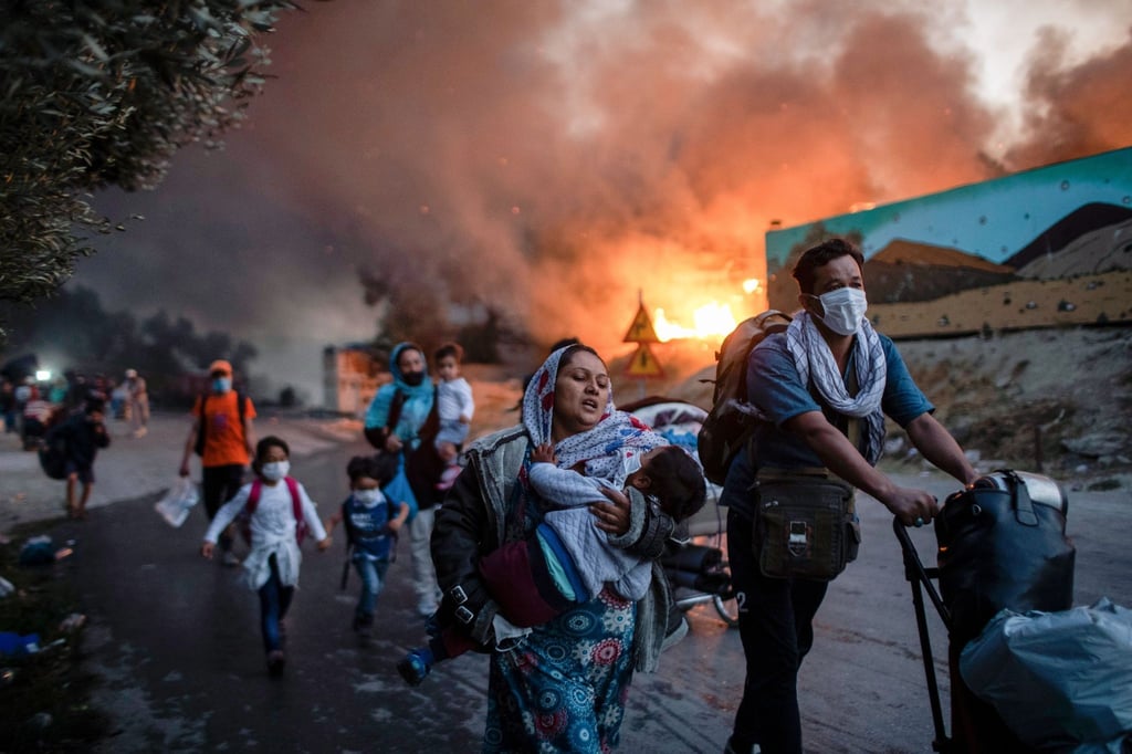 Migranten fliehen vor einem großen Feuer mit ihren Habseligkeiten aus dem Flüchtlingslager Moria.