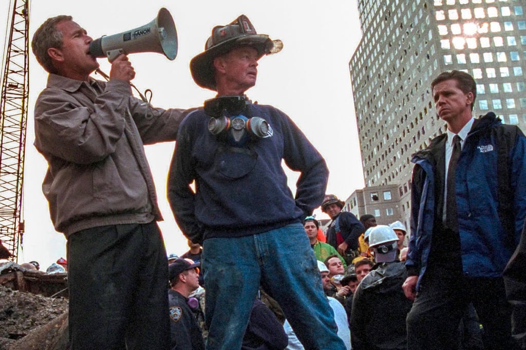 US-Präsident George W. Bush spricht in den Trümmern des New Yorker World Trade Centers neben dem pensionierten New Yorker Feuerwehrmann Bob Beckwith zu den freiwilligen Helfern und Feuerwehrleuten durch ein Megafon.