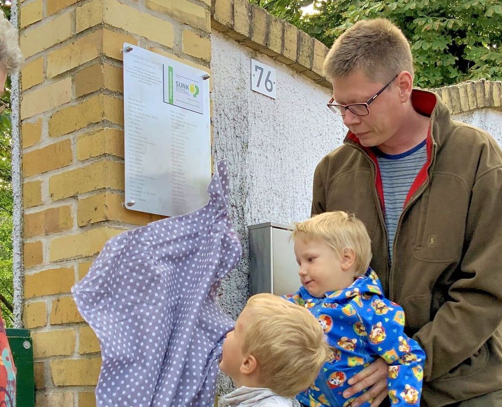 Finn und Linus enthüllen gemeinsam mit Vater Michael Stecher die Tafel am Gutspark, auf der alle Sponsoren der Baumaktion vermerkt sind.