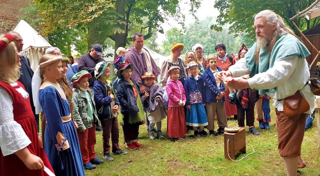 Die Tangermünder Stadtführerkinder lauschen dem Geschichtenerzähler.