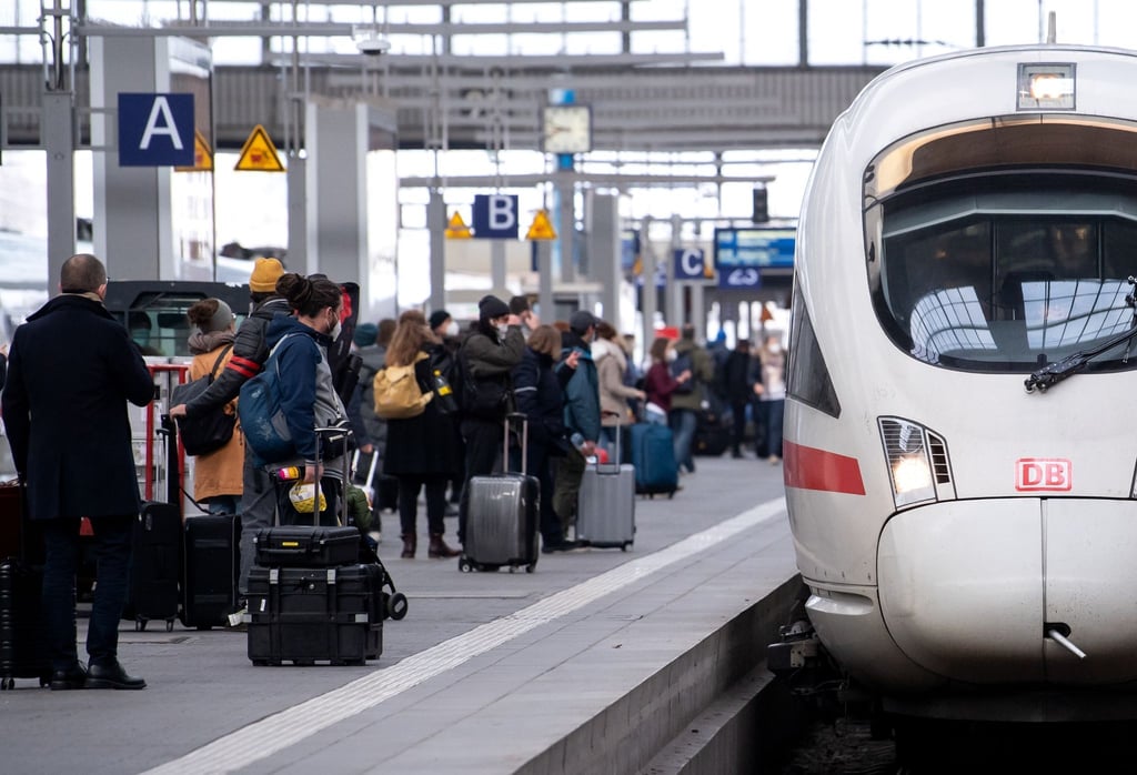 Reisende neben einem ICE am Münchener Hauptbahnhof.