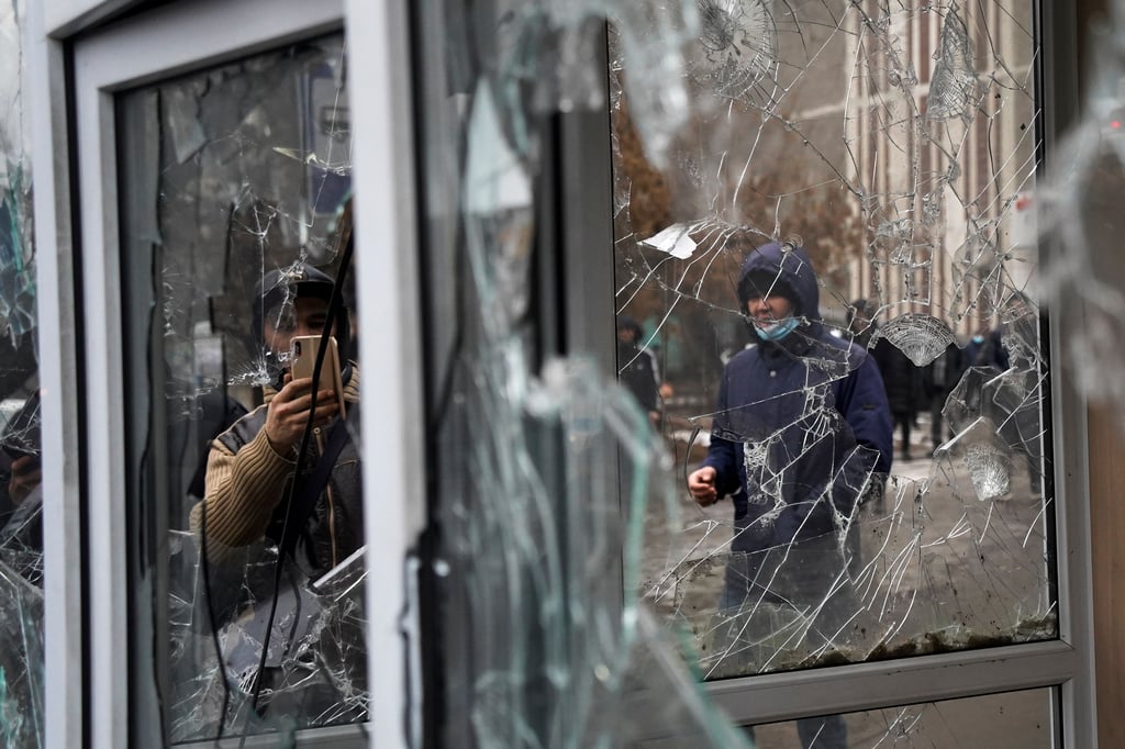 Ein Mann fotografiert die Fenster eines Polizeikiosks, die von Teilnehmern einer Demonstration beschädigt wurden. Aus Protest gegen hohe Energiepreise sind in Kasachstan in Zentralasien den dritten Tag infolge Tausende Menschen auf die Straße gegangen.
