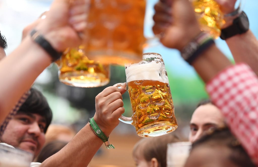 Besucher prosten sich in einem Bierzelt mit Biergläsern zu.