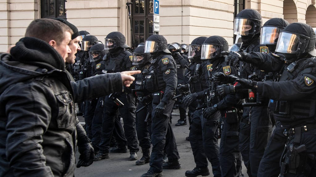 Ein Teilnehmer an der "Friedenswanderung" redet auf Polizisten ein. Die Demonstranten gingen durch Magdeburg, um gegen die Maßnahmen, die das Land Sachsen-Anhalt zur Eindämmung des Coronavirus erlassen hat, mit einer «Friedenswanderung» zu protestieren.