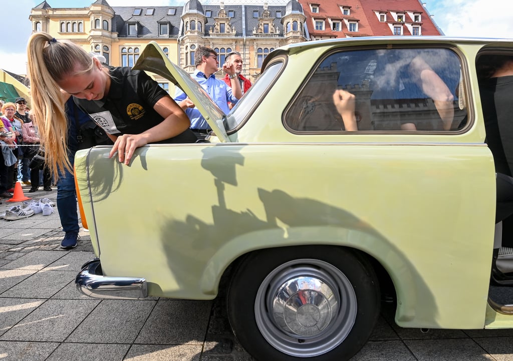 Spielerinnen des Handball-Bundesligisten BSV Sachsen Zwickau und Turnerinnen des Vereins "Fliegende Sachsen" steigen auf dem Markt in Zwickau in einen Trabant 601.
