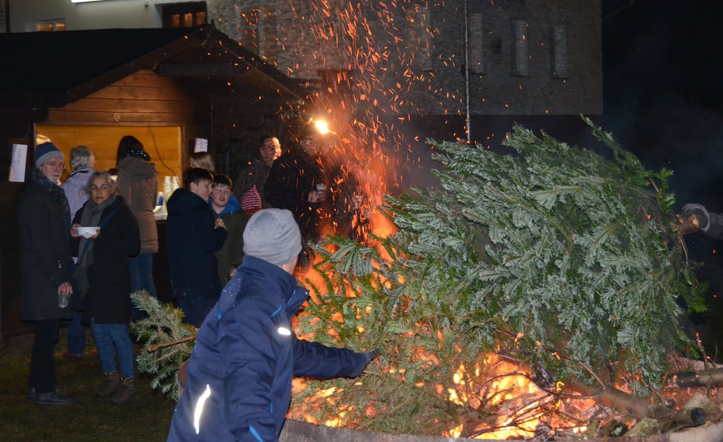 Feuerwehrmann Nico Panhans versorgt das Weihnachtsbaumfeuer im Garzer Hafen mit neuer Nahrung.