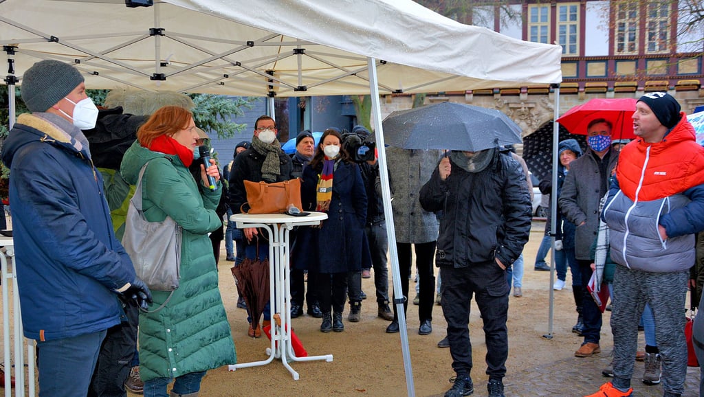 Oberbürgermeister Daniel Szarata und Amtsärztin Heike Christiansen (vorn links) diskutieren mit Bürgern auf dem Halberstädter Domplatz über die Coronaregeln.