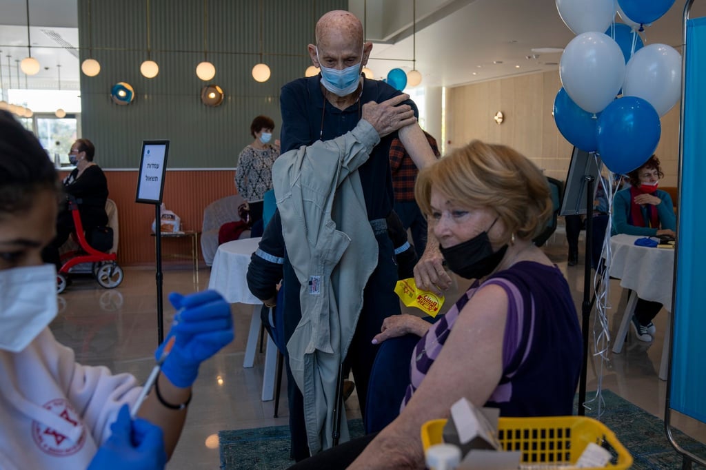 Ein Mann zieht sein Hemd hoch, während seine Frau ihre vierte Dosis des Coronavirus-Impfstoffs in einem privaten Pflegeheim in Petah Tikva erhält.