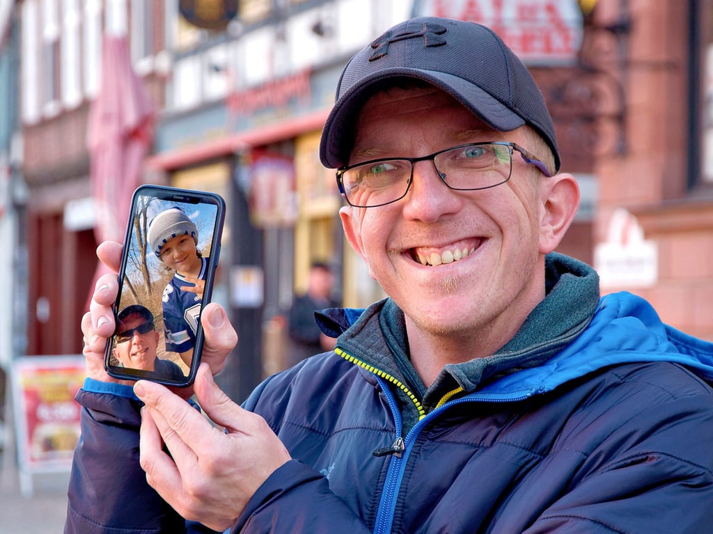 Der Wernigeröder Mario Scharfe zeigt ein Foto auf seinem Smartphone, auf dem er und sein genetischer Zwilling, der Texaner Riley Moss, zu sehen sind.