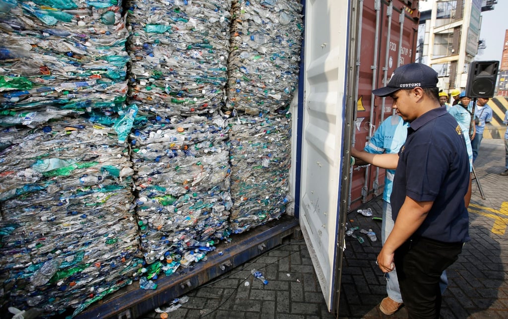 Ein Zollbeamter verschließt am Hafen von Tanjung Priok einen Container mit Plastikmüll.