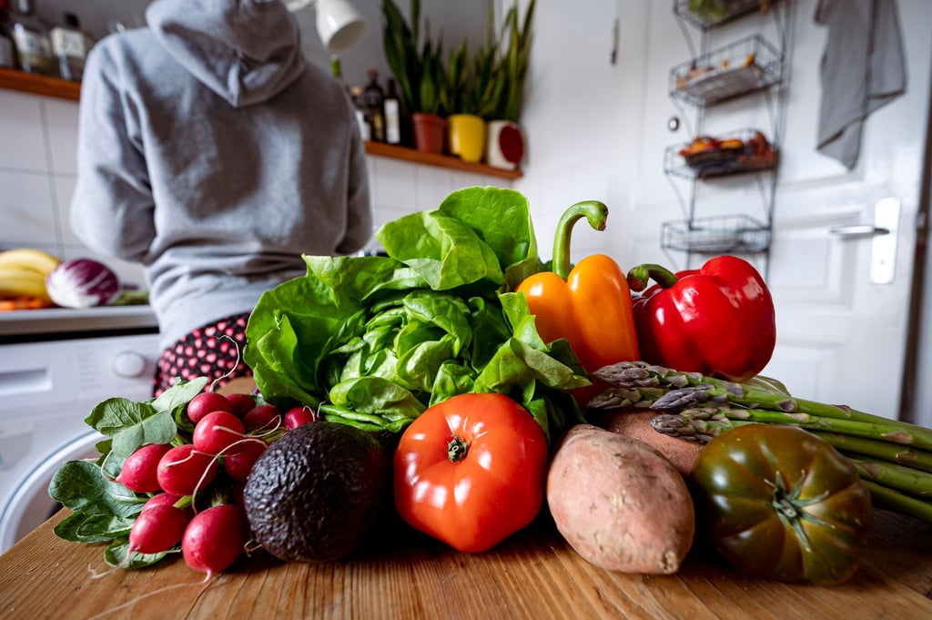 Eine junge Frau verarbeitet Gemüse in der Küche. Für Kinder wird eine rein pflanzliche Ernährung von Fachgesellschaften nicht empfohlen